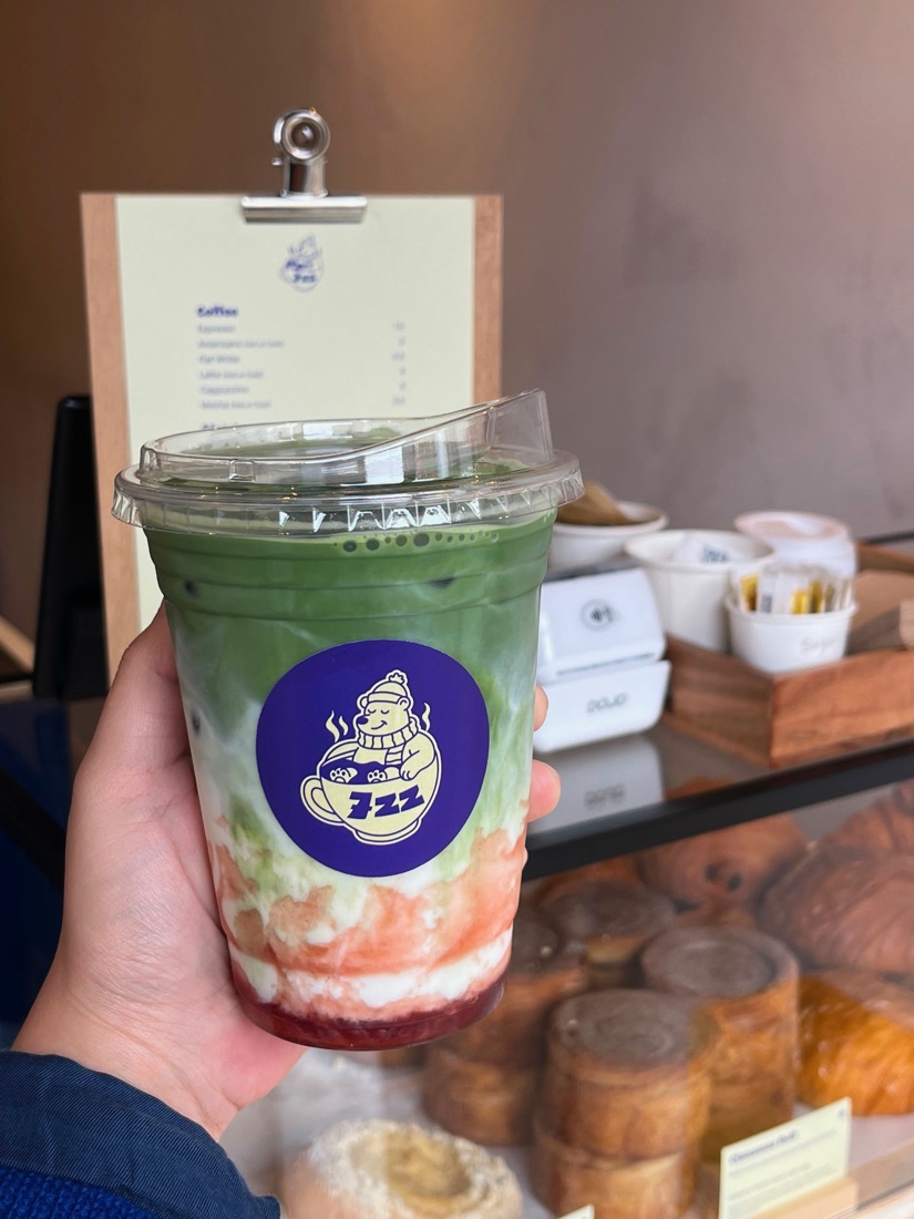 An iced strawberry matcha held up inside 7ZZ, a specialty coffee shop in Ancoats, Manchester